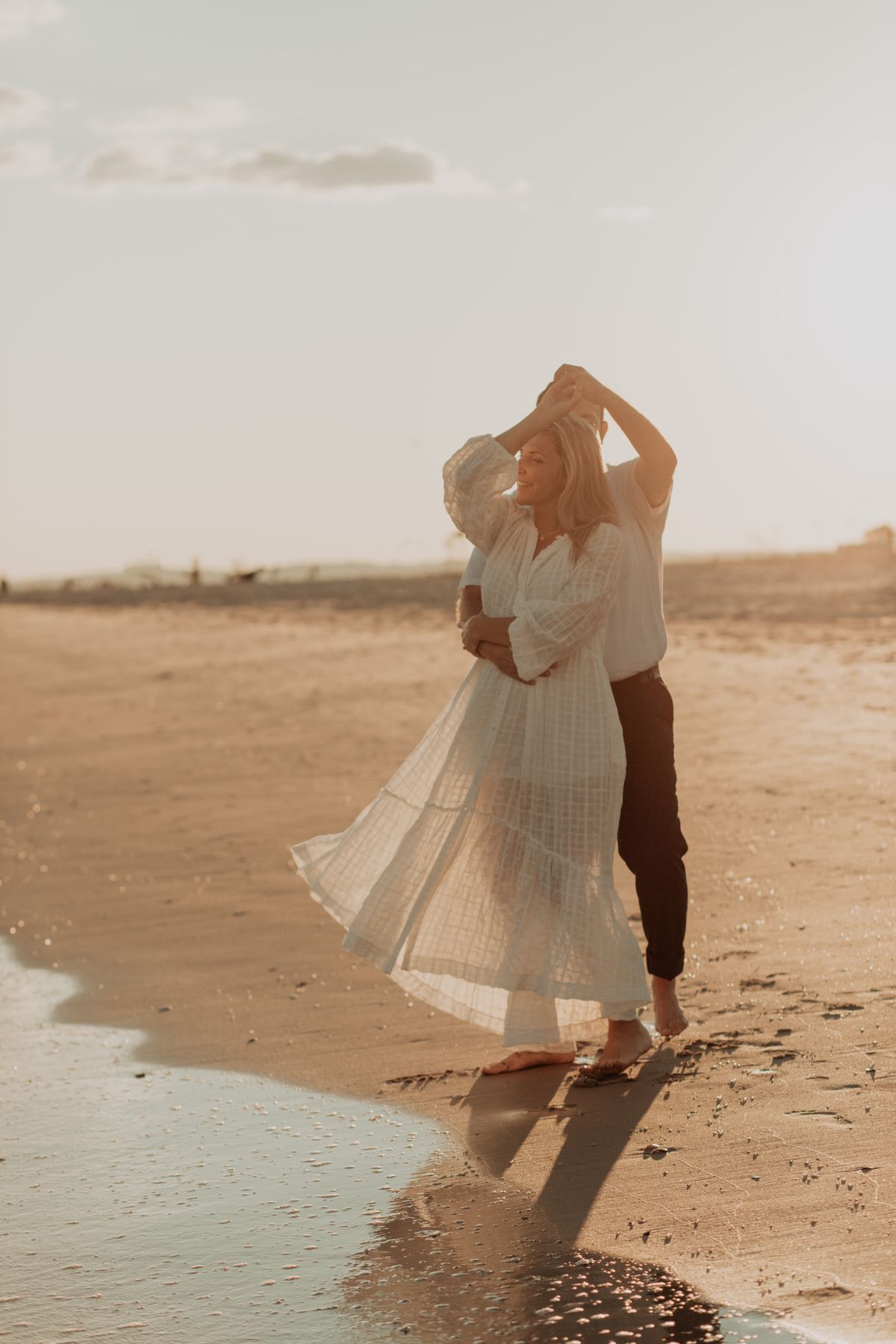 Sarah and Daniel dancing together on the beach at sunset
