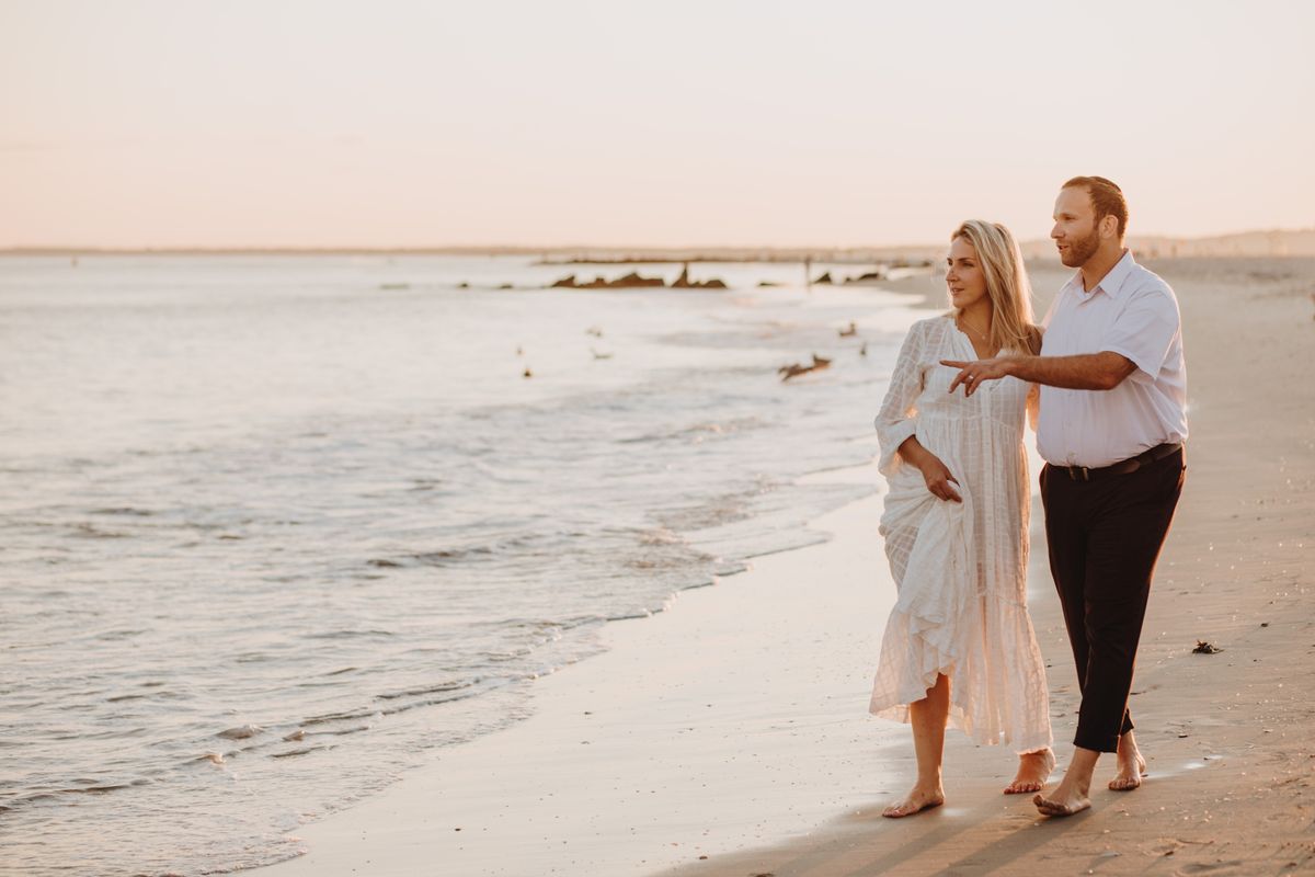 Sarah and Daniel walking beside the ocean at sunset